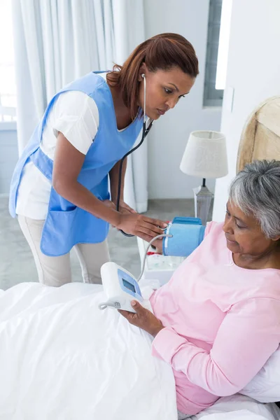 Médico midiendo la presión arterial de la mujer mayor — Foto de Stock