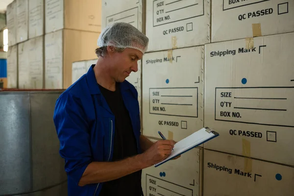 Worker writing on clipboard in olives factory — Stock Photo, Image