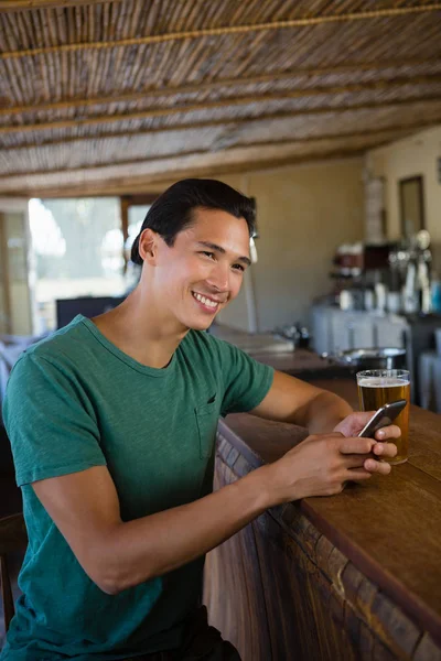 Mężczyzna patrząc od hotelu podczas korzystania z telefonu w barze — Zdjęcie stockowe