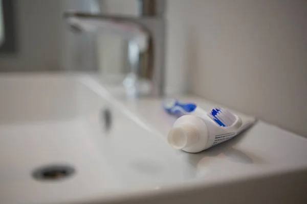 Tubo de pasta de dentes e escova de dentes na pia do banheiro — Fotografia de Stock