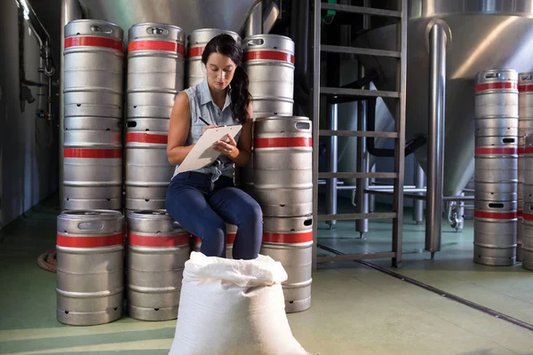 Female worker writing on clipboard in factory — Stock Photo, Image