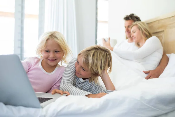 Family using digital tablet and laptop on bed — Stock Photo, Image