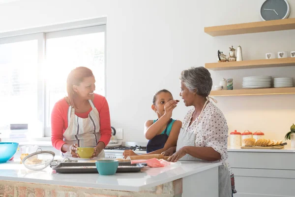 Meisje voeding voedsel aan haar grootmoeder in keuken — Stockfoto