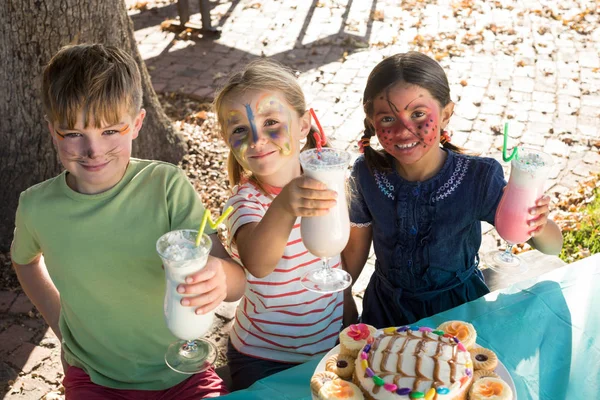 Kinderen houden van de dranken aan tafel in het park — Stockfoto