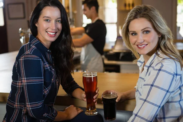 Vriendinnen met de barman in achtergrond — Stockfoto