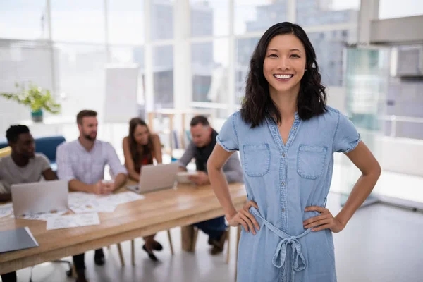 Female executive standing with hands on hip in the office — Stock Photo, Image