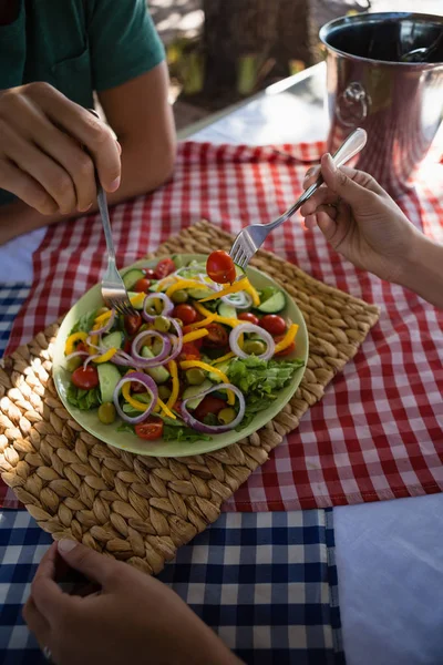 Mani tagliate di amici che hanno insalata a tavola — Foto Stock