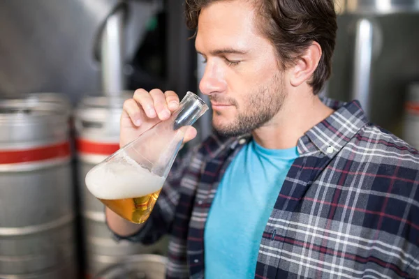 Homme examinant la bière dans le bécher — Photo