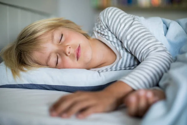 Menino dormindo na cama no quarto — Fotografia de Stock