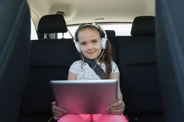 Девушка слушает музыку на наушниках из цифрового планшета — стоковое фото