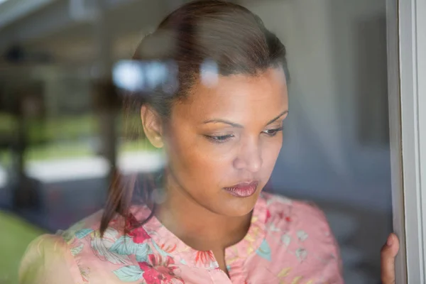 Vrouw op zoek via venster thuis — Stockfoto