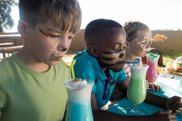 Crianças com pintura facial tendo bebidas — Fotografia de Stock