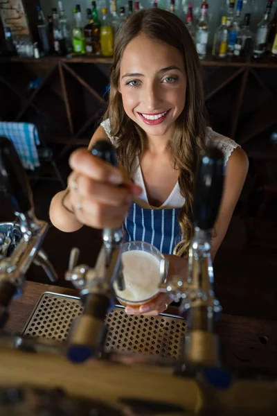 Барменша наливает пиво из крана в стекло — стоковое фото