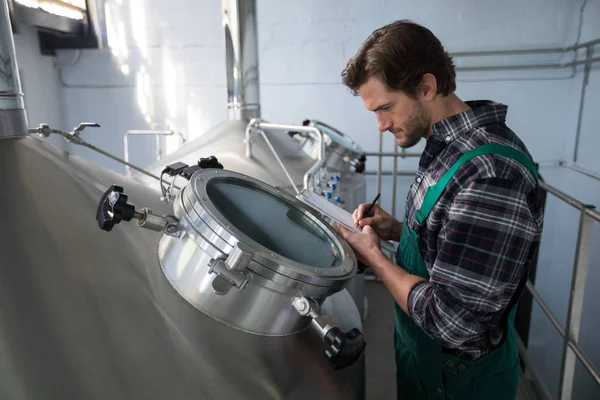 Worker examining storage tanks — Stock Photo, Image