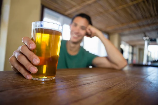 Homem segurando copo de cerveja no balcão de bar — Fotografia de Stock