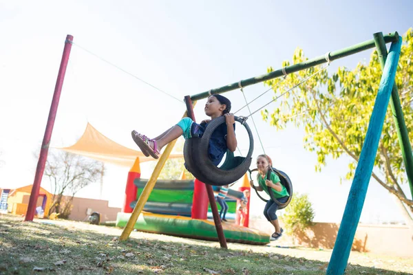 Meninas balançando no playground contra o céu — Fotografia de Stock