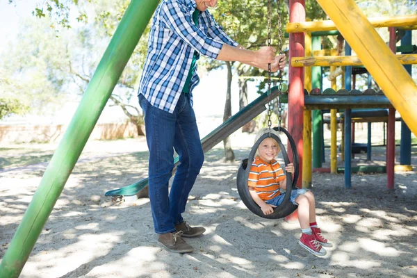 Padre empujando hijo sentado en swing — Foto de Stock