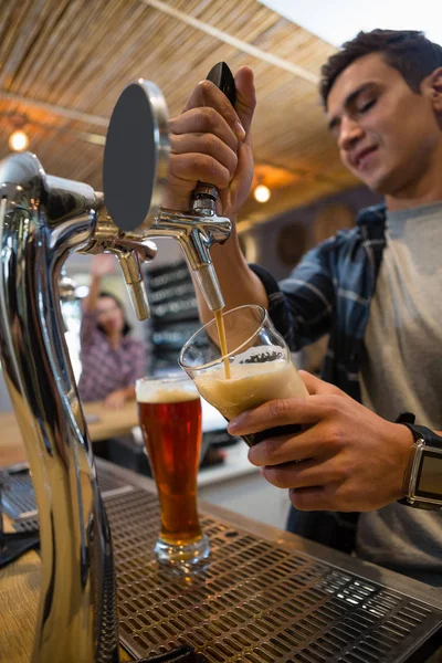 Barman drinken uit de kraan in glas gieten — Stockfoto