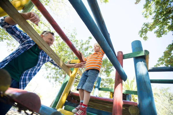 Father looking at son walking on jungle gym — Stock Photo, Image