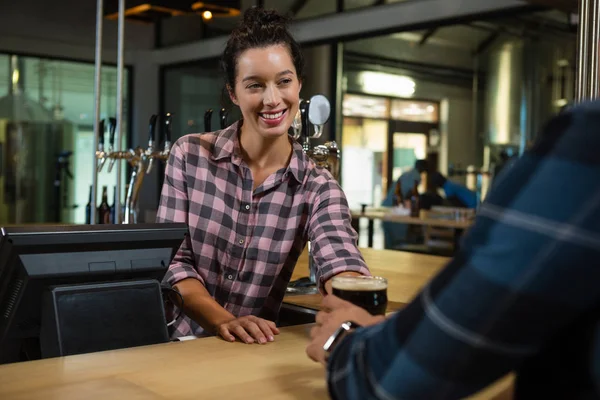 Young barmaid serving drink to man — Stock Photo, Image