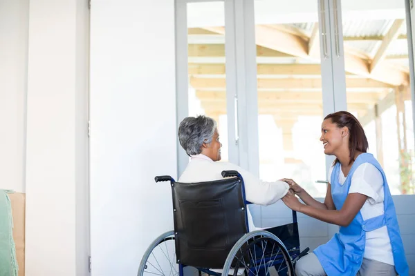 Medico che interagisce con la donna anziana sulla sedia a rotelle — Foto Stock