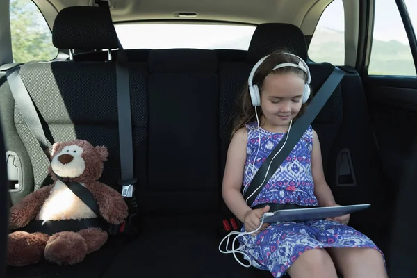 Menina ouvindo música no fone de ouvido do tablet — Fotografia de Stock