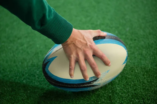 Mão cortada segurando bola de rugby — Fotografia de Stock