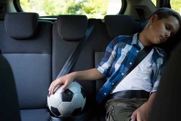 Tonårspojke som sitter med fotboll i bilen — Stockfoto