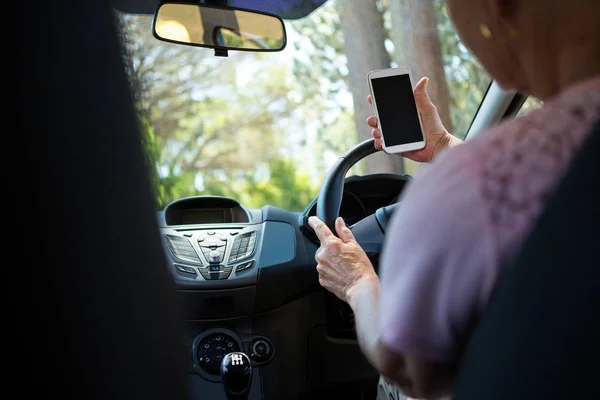 Donna anziana utilizzando il telefono durante la guida di auto — Foto Stock