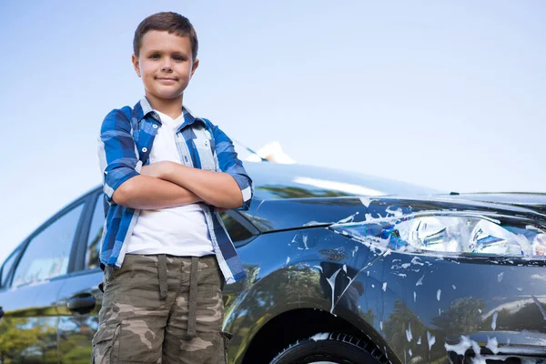 Teenage boy standing with arms crossed near car — Stock Photo, Image