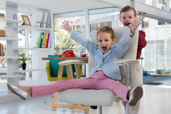 Boy als bedrijfsleiders duwen collega op stoel — Stockfoto