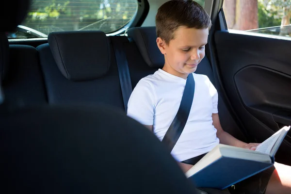Chłopiec czytanie książki w tylnym siedzeniu samochodu — Zdjęcie stockowe