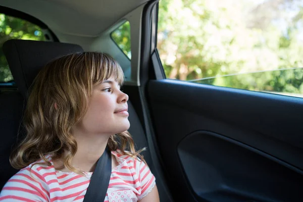 Chica adolescente sentada en el asiento trasero del coche — Foto de Stock