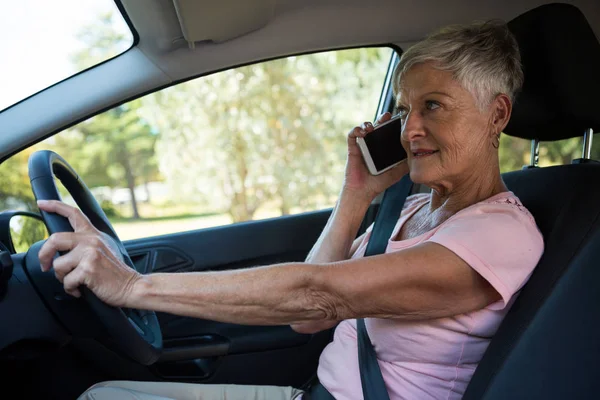 Senior woman talking on phone in car