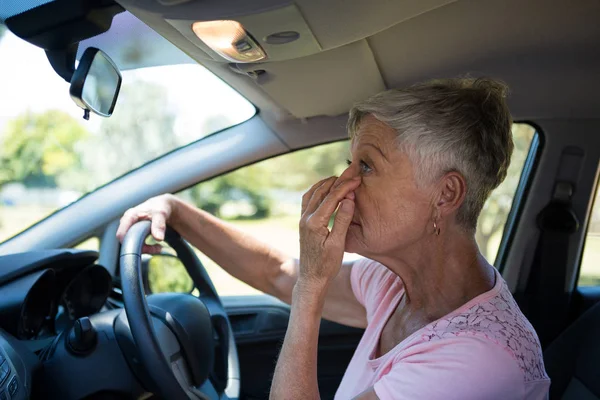 Senior woman looking into rear view mirror — Stock Photo, Image