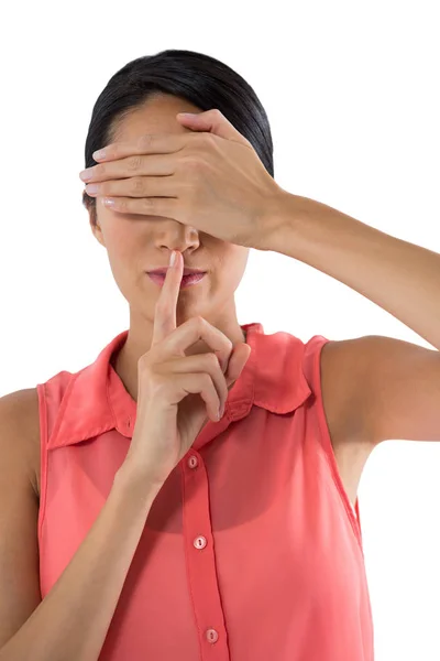 Woman covering her eyes with finger on lips — Stock Photo, Image