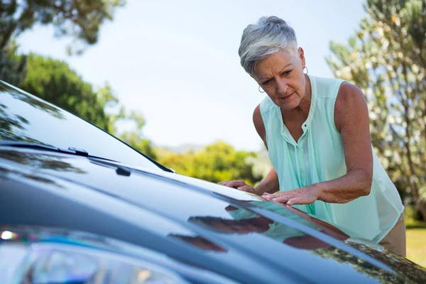 Mujer mayor revisando su coche — Foto de Stock