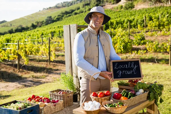 Homme debout avec ardoise au stand de légumes — Photo