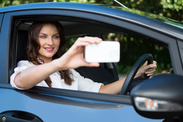 Женщина делает селфи с телефоном в машине — стоковое фото