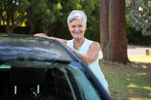 Femme âgée debout à côté d'une voiture — Photo