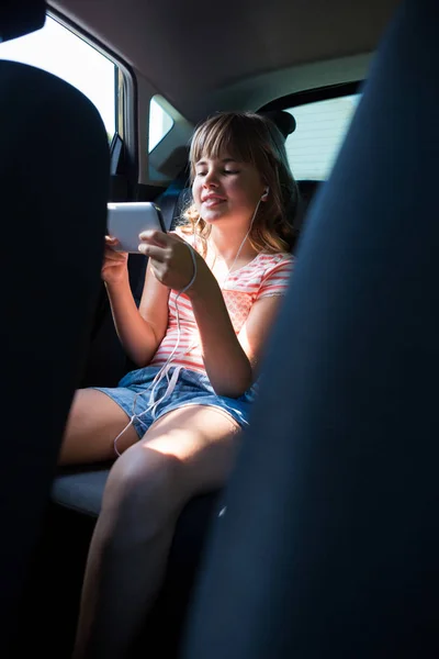 Девушка-подросток в наушниках с помощью телефона — стоковое фото