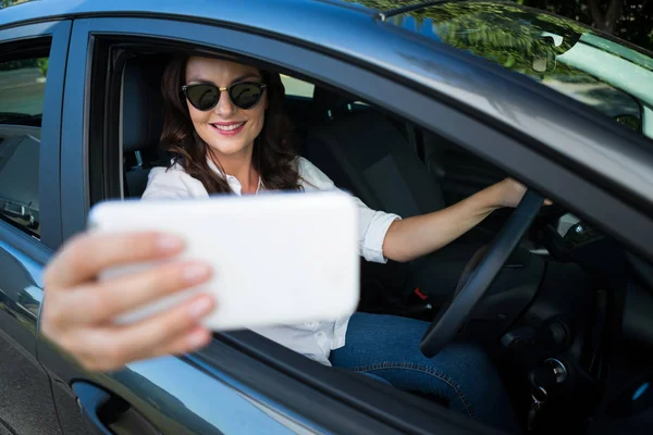 Kvinnan tar selfie med telefon i bilen — Stockfoto