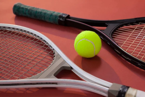 Fluorescerande gul boll mitt tennisracketar — Stockfoto