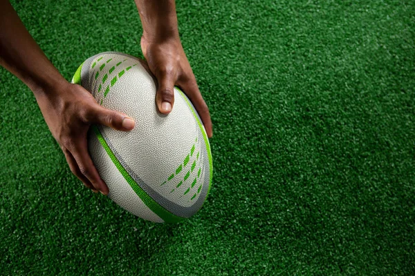 Manos sosteniendo pelota de rugby — Foto de Stock