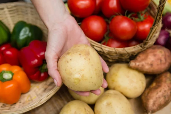 Mujer sosteniendo papa fresca en puesto de verduras — Foto de Stock