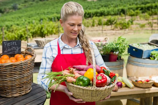 Vrouw met een korf van verse groenten op stal — Stockfoto