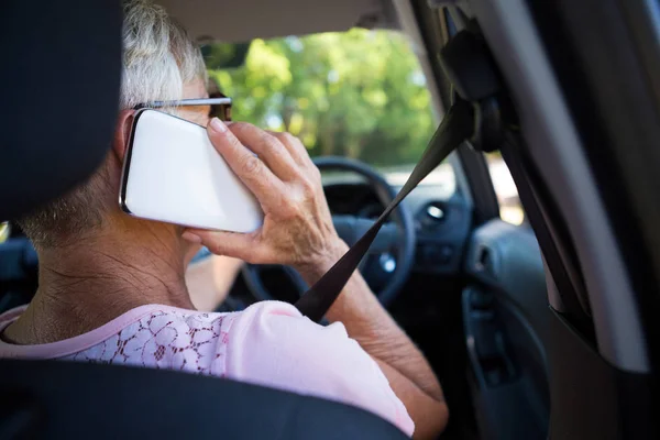Старшая женщина разговаривает по телефону в машине — стоковое фото