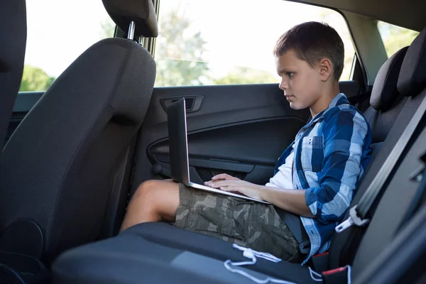 Nastoletniego chłopca za pomocą laptopa w samochodzie — Zdjęcie stockowe