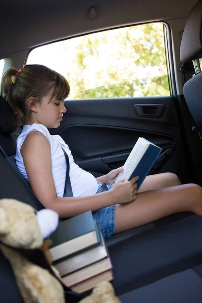 Kız okuma kitabı arabanın arka koltuğunda — Stok fotoğraf
