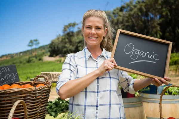 Portrait of happy woman holding slate with text in vineyard — Stock Photo, Image